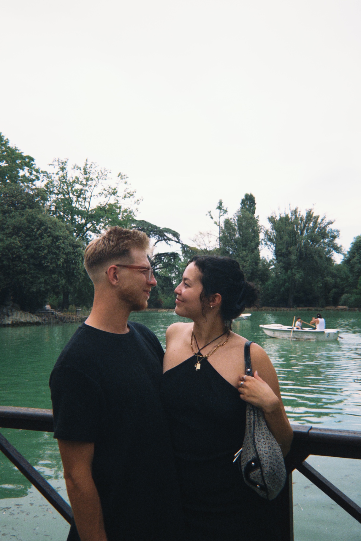 Jono & Monika facing each other on a walkway beside a lake